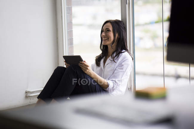 Businesswoman working barefoot on floor in modern office — job, tablet -  Stock Photo | #178147384