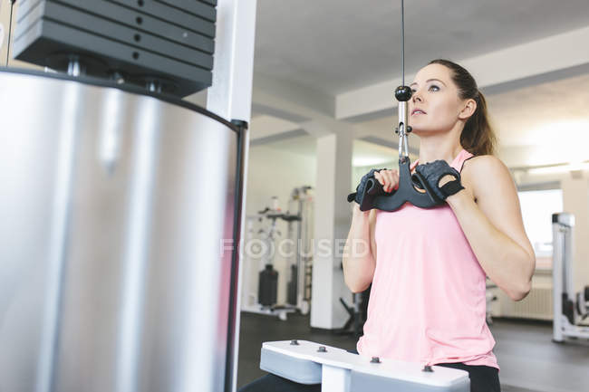 Woman doing cable pulldowns in gym — Stock Photo