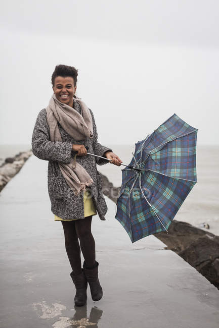 Mulher segurando guarda-chuva em um dia chuvoso em frente ao mar — Fotografia de Stock