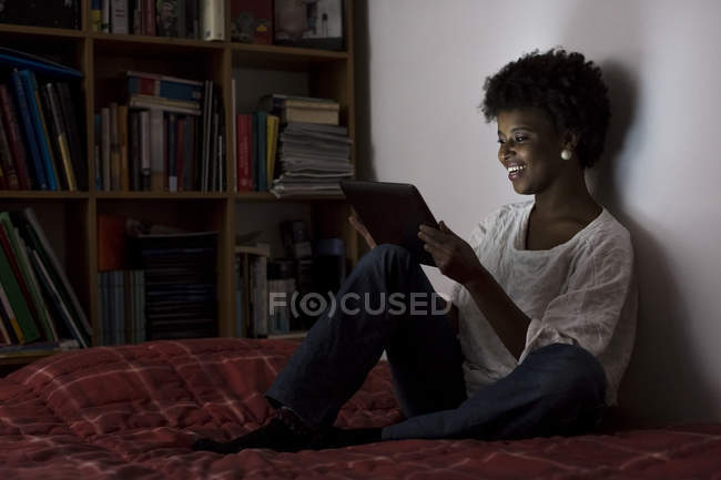 Junge Frau sitzt zu Hause mit digitalem Tablet auf ihrem Bett — Stockfoto