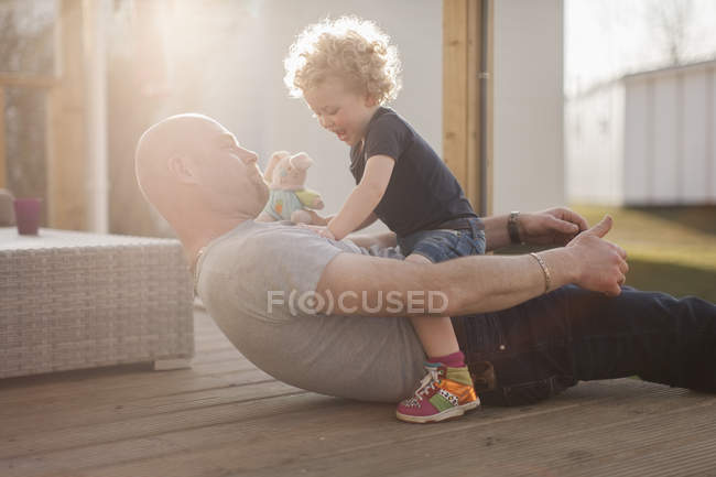 Padre jugando con la pequeña hija en la terraza - foto de stock