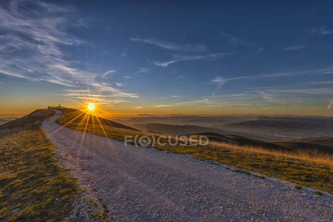 Italia, Umbria, Valsorda, Tramonto sull'eremo di Serrasanta e veduta della strada — Foto stock