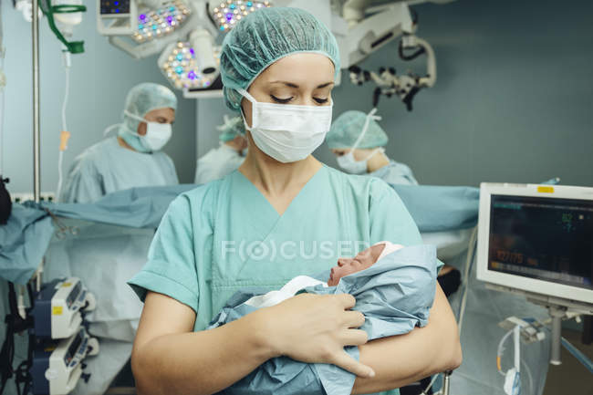 Медсестра операционной держит новорожденного в операционной — стоковое фото