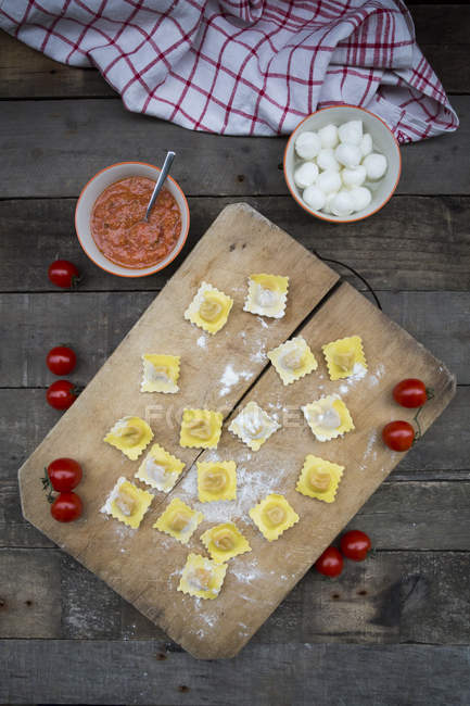 Homemade noodles, ravioli, filled with tomato mozzarella on chopping board — Stock Photo