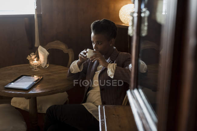 Pensive jovem mulher sentada em um café bebendo café — Fotografia de Stock