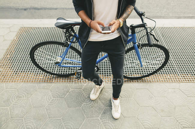 Adolescente com uma fixação de mensagens de bicicleta na rua da cidade — Fotografia de Stock