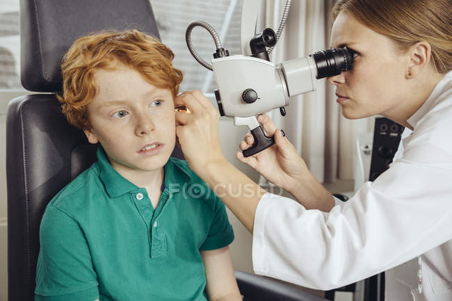 Médica examinando menino com microscópio — Fotografia de Stock