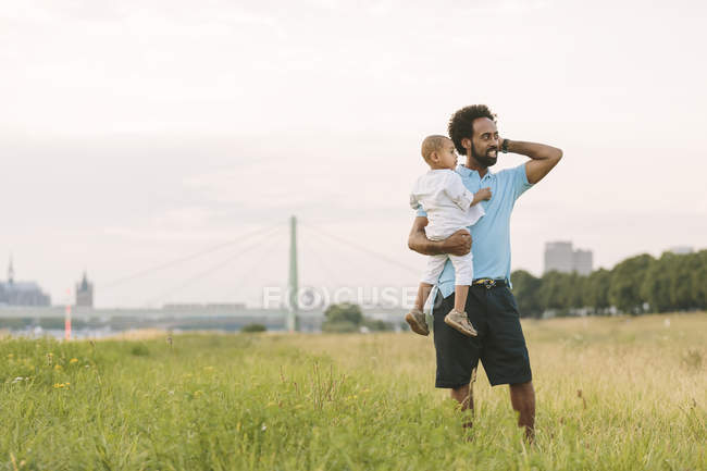 Felice padre afroamericano che porta suo figlio sul campo — Foto stock