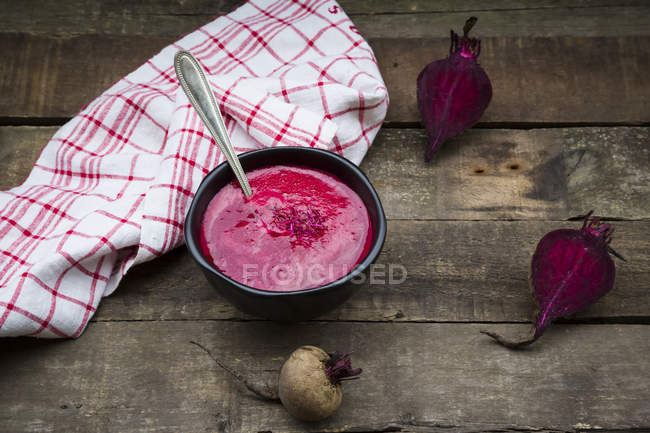 Bowl of beetroot soup garnished with beetroot sprouts on dark wood — Stock Photo