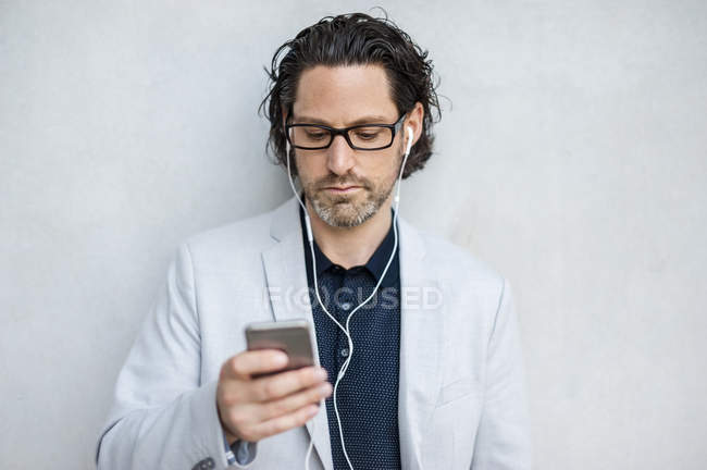 Uomo d'affari che utilizza smartphone con auricolari — Foto stock
