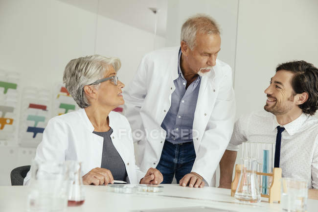 Three scientists talking in modern lab — Stock Photo