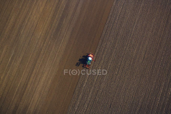 Вид с воздуха на сельскохозяйственный трактор, работающий на поле днем, Австрия — стоковое фото