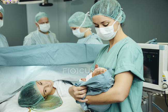 Infirmière de salle d'opération montrant le nouveau-né à la mère à l'hôpital — Photo de stock