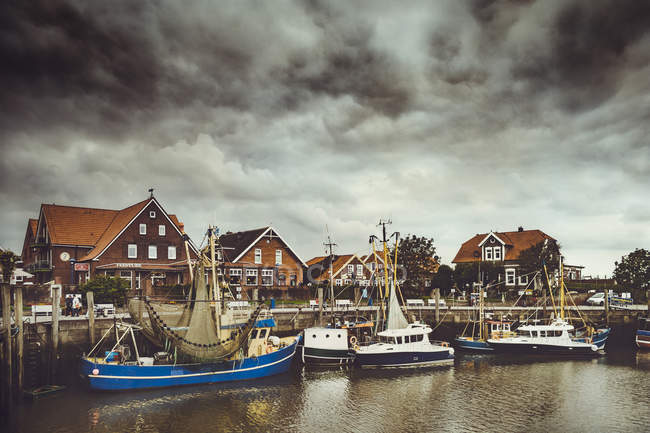 Germany, Lower Saxony, Greetsiel, Neuharlingersiel, fishing harbour and angry clouds — Stock Photo