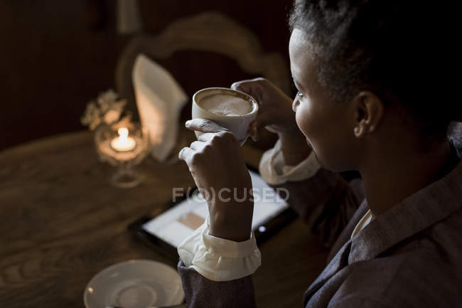 Young woman sitting in a cafe with cup of cappuccino — Stock Photo