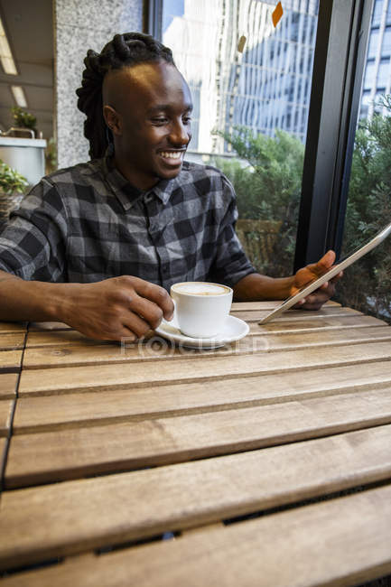 Junger Mann sitzt mit digitalem Tablet im Café — Stockfoto