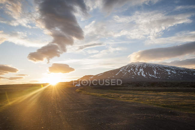 Distant view of car on gravel road under midnight sun, Iceland — Stock Photo