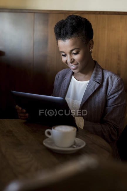 Young woman sitting in a cafe using digital tablet — Stock Photo