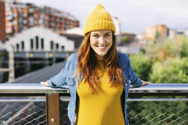 Portrait de jeune femme souriante portant un chapeau et une robe en laine jaune — Photo de stock
