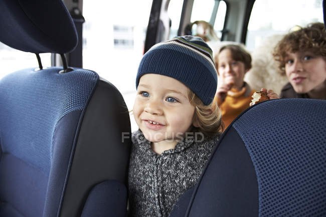 Menino sentado no carro com irmãos — Fotografia de Stock