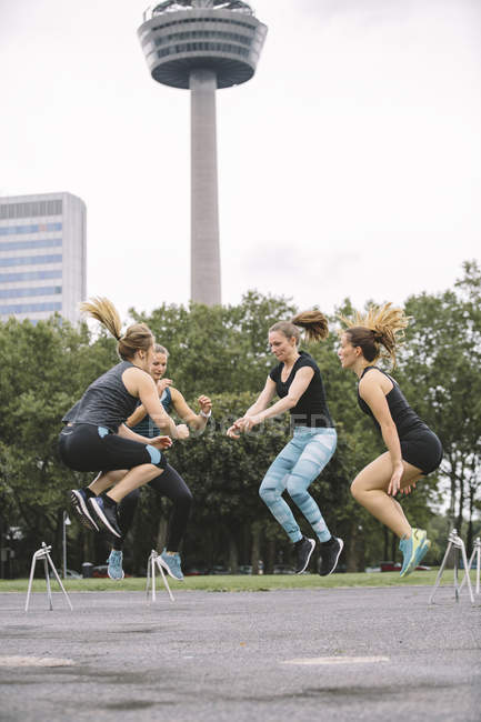 Quatro mulheres pulando durante o treino ao ar livre — Fotografia de Stock