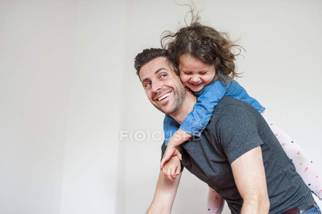 Счастливый отец носит дочь на спине — стоковое фото