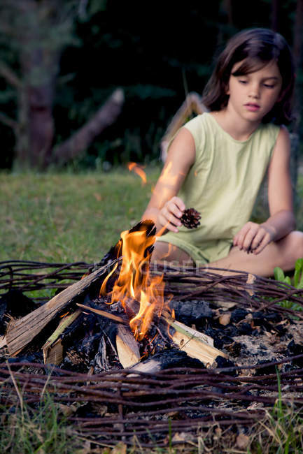 Дівчинка сидить на луг позаду табір вогню — стокове фото