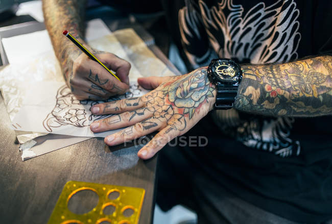 Cropped image of tattoo artist designing motifs at studio — Stock Photo