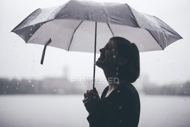 Laughing woman with umbrella on a rainy day — Stock Photo