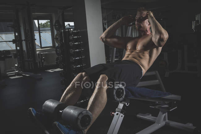 Atleta físico fazendo crunches no ginásio — Fotografia de Stock
