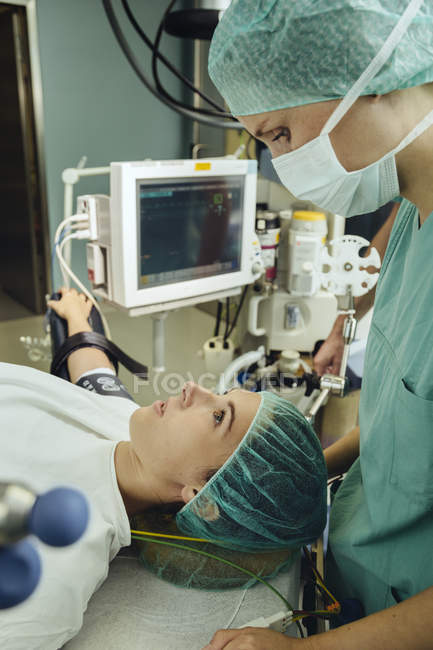 Жіночий операційні медсестра говорити до пацієнта на стіл в операційний зал — стокове фото