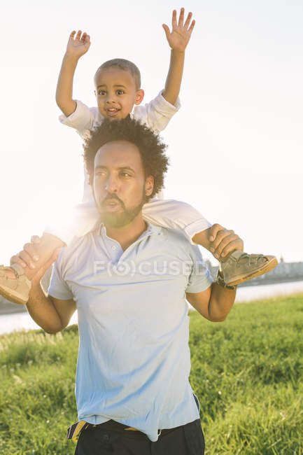 Father carrying son on shoulders at nature — Stock Photo
