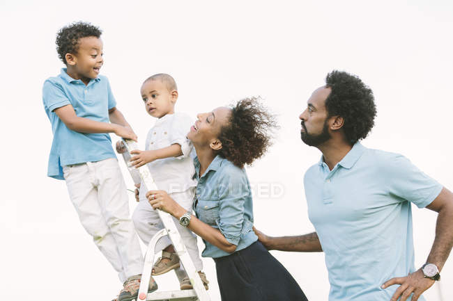 Happy african american parents looking at two sons on ladder — Stock Photo