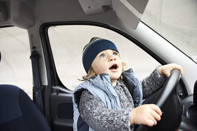 Niño sentado en el volante del coche - foto de stock
