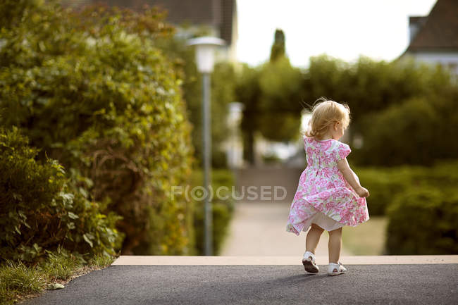 Visão traseira da menina loira vestindo vestido com design floral — Fotografia de Stock