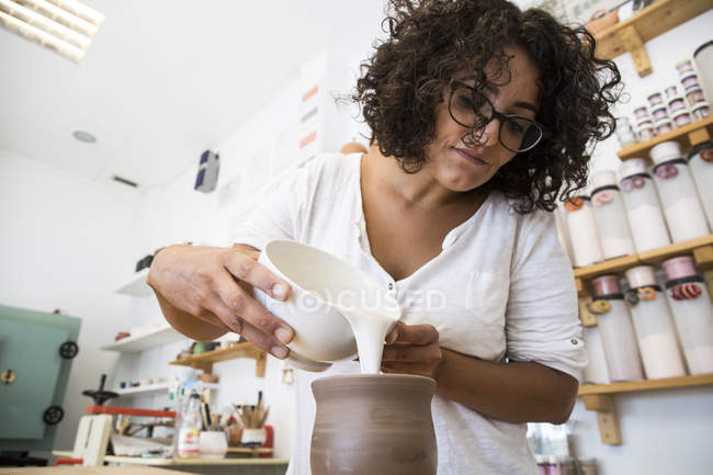 Taza de cerámica esmaltada mujer en taller - foto de stock
