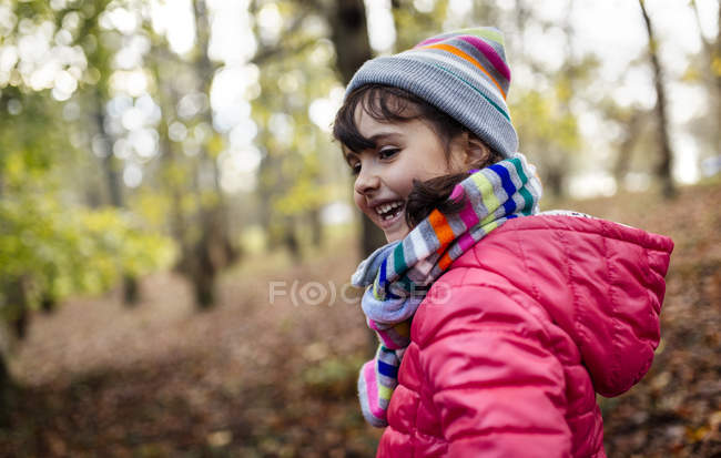 Щаслива маленька дівчинка в лісі в шапці і шарфі восени — стокове фото