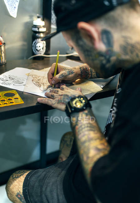 Tattoo artist designing motifs at studio — Stock Photo