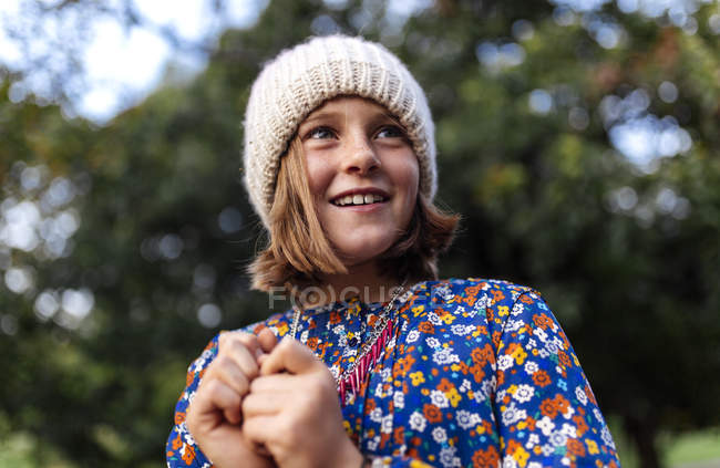 Menina sorrindo vestindo boné de lã olhando para os lados — Fotografia de Stock