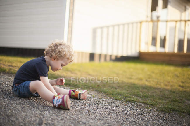 Little girl sitting on gravel path — Stock Photo
