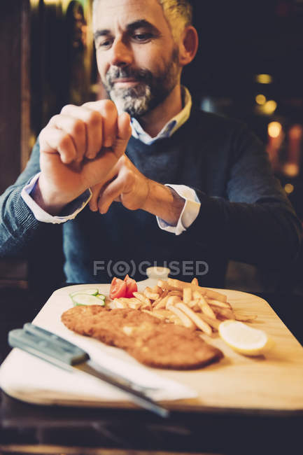 Man in restaurant having Wiener Schnitzel with French fries — Stock Photo
