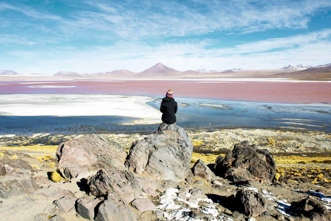 Bolivia, Potosí, Mujer admirando Laguna Colorada sentada sobre roca - foto de stock