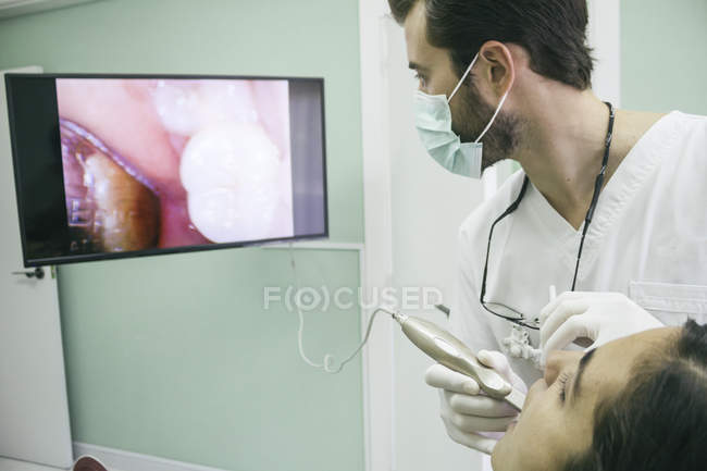 Стоматолог осматривает рот пациента внутриротовой камерой — стоковое фото