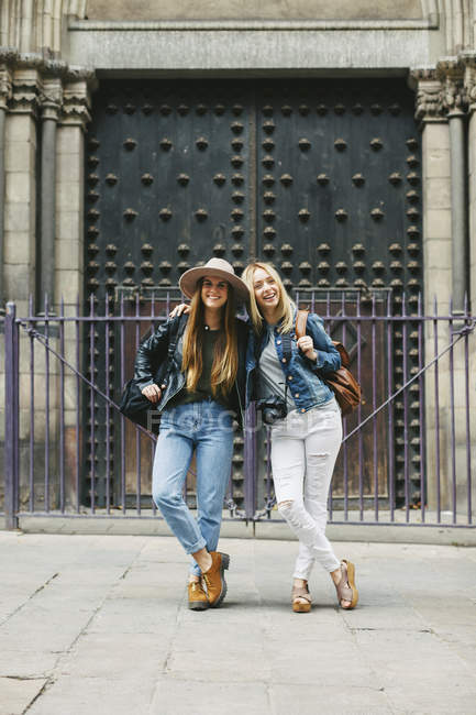 España, Barcelona, dos mujeres jóvenes frente al portal de entrada - foto de stock