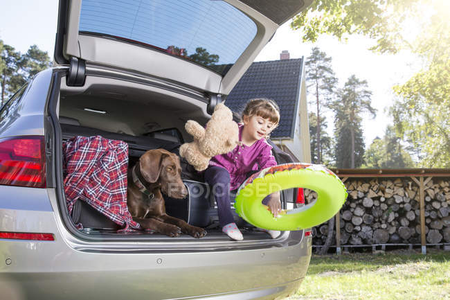 Ragazza che gioca in auto stivale con cane e orsacchiotto — Foto stock
