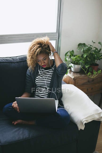 Frau benutzt Laptop auf Couch — Stockfoto