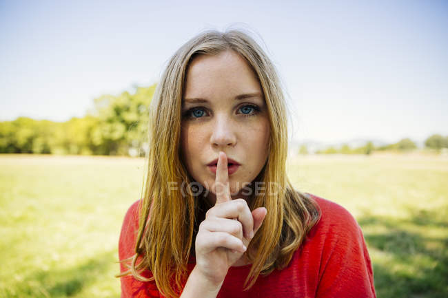 Retrato de adolescente al aire libre poniendo el dedo en la boca - foto de stock