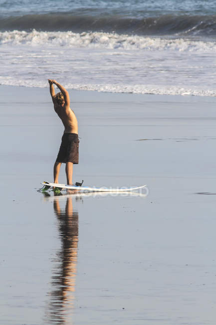 Surfeur masculin étirant sur la plage — Photo de stock