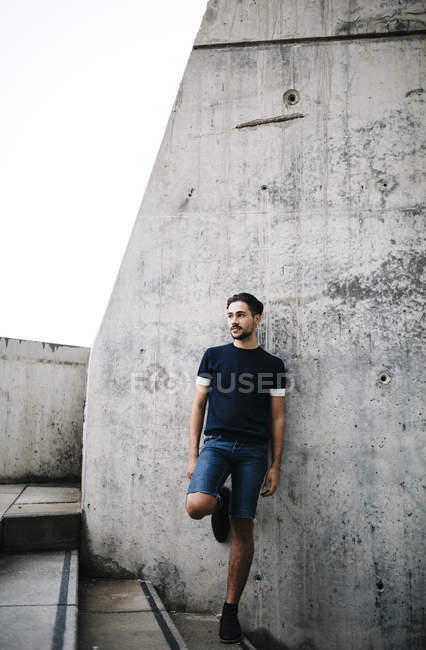 Young man leaning against concrete wall — Stock Photo