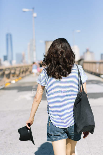 USA, New York, vista posteriore di una giovane donna che cammina sul ponte di Brooklyn — Foto stock